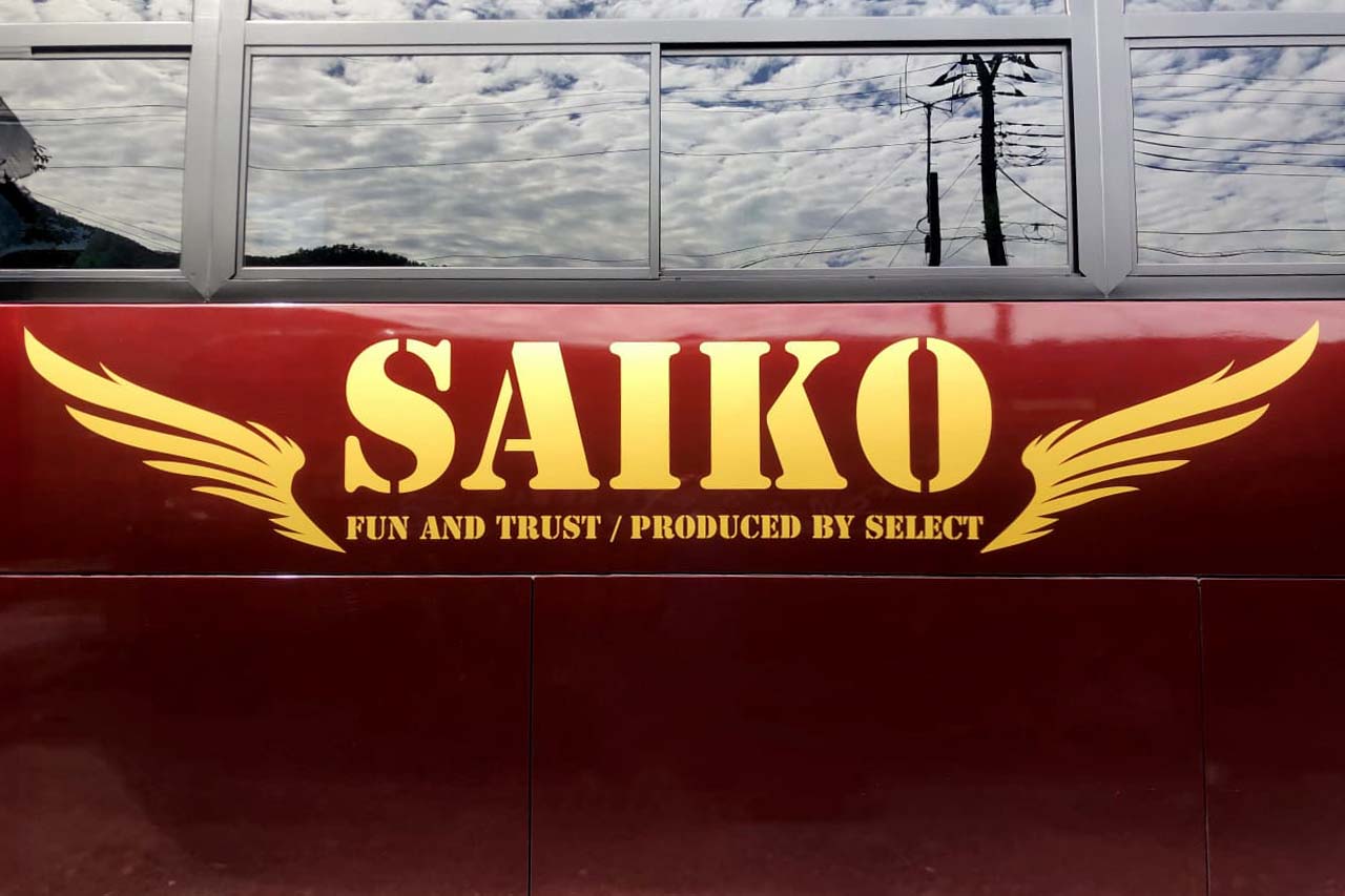 観光バスの外装に描かれたロゴ。SAIKO - FUN AND TRUST / RRODUCED BY SELECT